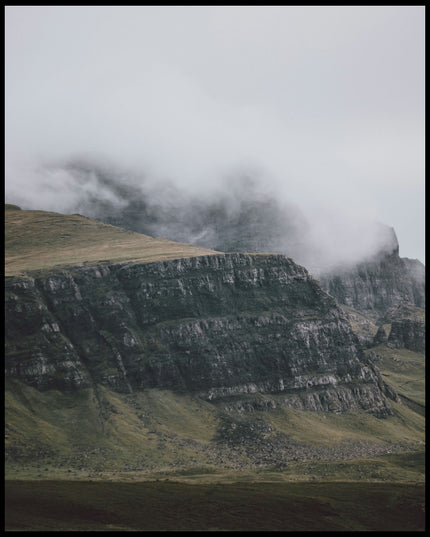 Leinwandbild von einem steilen Abhang eines Berges, der von Gras bedeckt und von Nebel umschlungen ist.