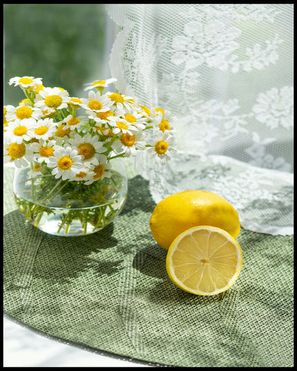 Leinwandbild von zwei Zitronen und Blumen in einem Glas auf einer grünen Unterlage aus Stoff.