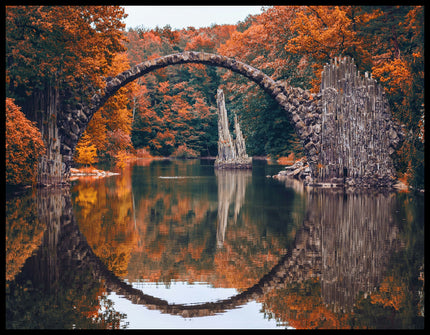 Ein Poster von der Seitenansicht einer freispannenden Bogenbrücke in einem herbstlichen Wald und über einem ruhigen See.