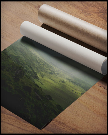 Ein Poster von einer grünen Landschaft in Irland mit Sonnenstrahlen, gerollt auf einer Holzoberfläche liegend