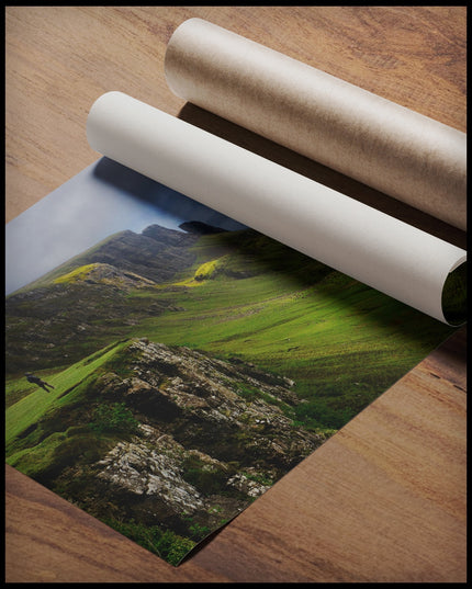 Ein Poster von grasbewachsenen Bergformationen auf der schottischen Insel Skye, gerollt auf einer Holzoberfläche liegend