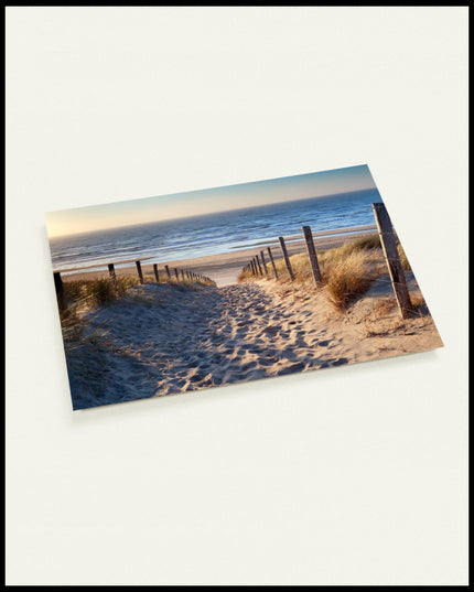 Eine Postkarte von Fußspuren im Sand auf einem Sandweg zum Strand.